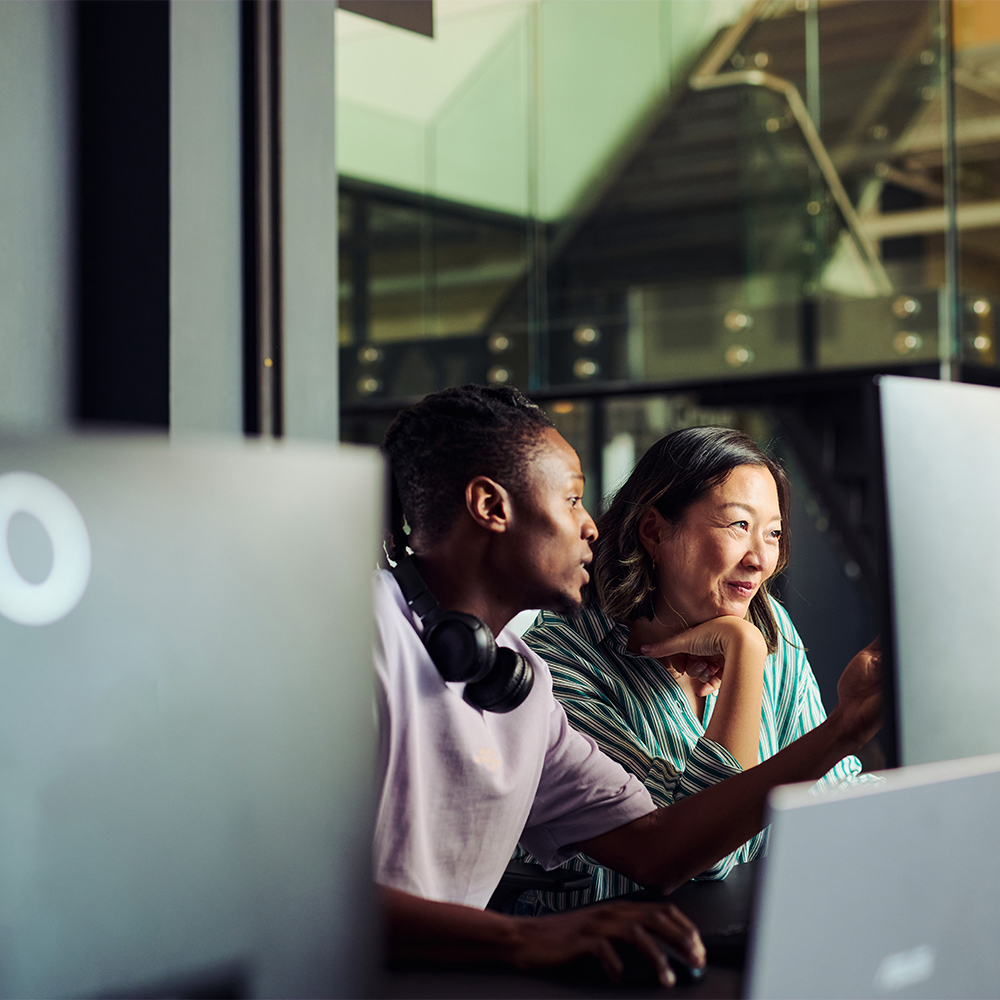 A Shopify migration expert collaborates with a client, pointing at a computer screen to guide them through the successful transition of their e-commerce store to the new platform.