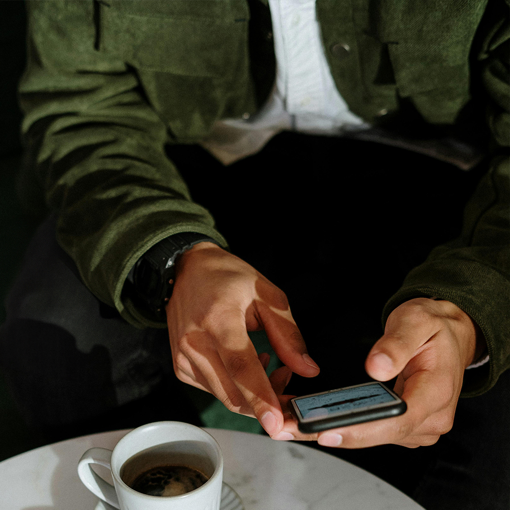 A store owner accesses powerful Shopify features on their smartphone, easily managing their business from a café table with a coffee.