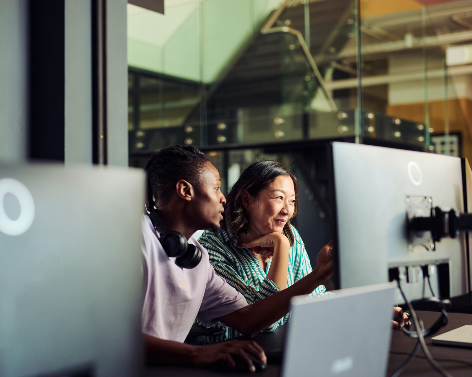 A Shopify migration expert collaborates with a client, pointing at a computer screen to guide them through the successful transition of their e-commerce store to the new platform.